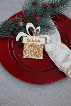 a red plate topped with a christmas ornament next to a napkin and tree branch