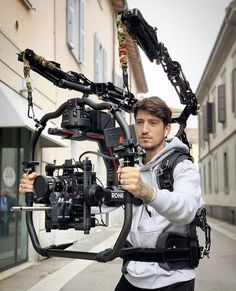 a man holding up a camera on the side of a road with multiple cameras attached to it