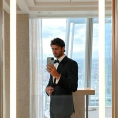 a man in a tuxedo is taking a selfie with his cell phone