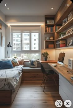 a bedroom with a bed, desk and computer on top of wooden shelves in front of a window