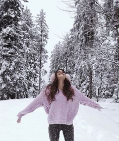 a woman is standing in the snow with her arms spread out and eyes wide open