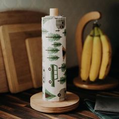 a wooden table topped with bananas next to a vase filled with green leaves and trees