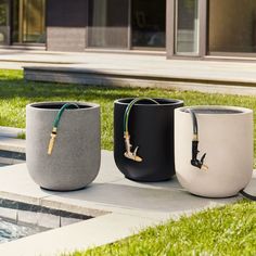 three different colored vases sitting next to each other on the ground in front of a pool