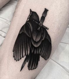 a black bird with a knife in its beak on the leg tattoo design for men