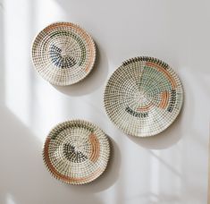 three woven baskets with designs on them sitting on a table