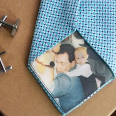 a blue tie with a photo on it next to a pair of silver cufflinks