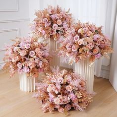 three vases filled with pink flowers on top of a wooden floor