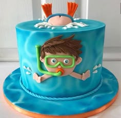 a blue cake with a boy wearing goggles and diving gear on it's side