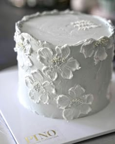 a white cake with flowers on it sitting on top of a table next to a magazine