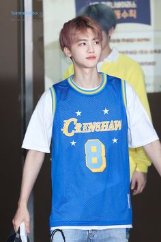 a young man wearing a blue basketball jersey and carrying a black bag in his hand