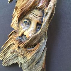 a wooden carving of a man's face with blue eyes