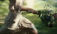 a blurry image of a woman holding flowers in her hands and running through the grass