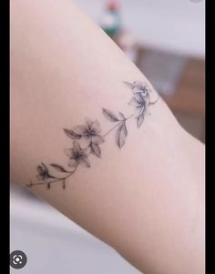 a woman's arm with a tattoo on it that has flowers growing out of it