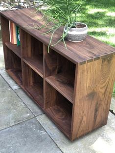 a wooden shelf with some books and a potted plant on top