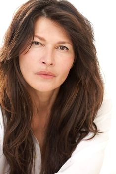 a woman with long hair is posing for the camera and looking at the camera while wearing a white shirt