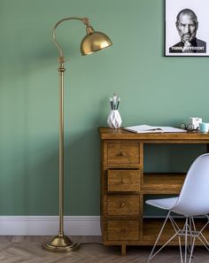 a desk with a chair and a lamp in front of a painting on the wall