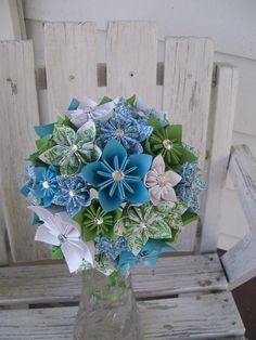 a vase filled with paper flowers on top of a wooden bench