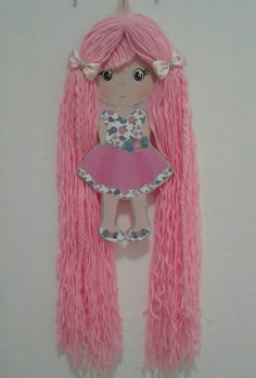 a pink doll with long hair hanging from a hook on a wall next to clothes pins