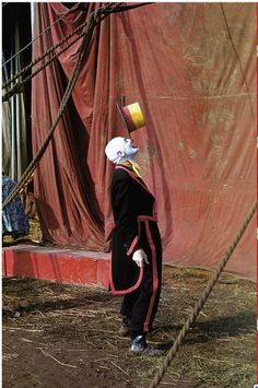 a man with a bucket on his head standing in front of a red tarp