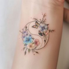 a woman's tattoo with flowers and butterflies on her left arm, in the shape of a yin - yang