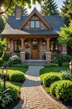 a small brick house surrounded by lush green trees and shrubbery, with a walkway leading to the front door