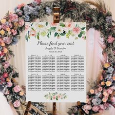 a floral wedding seating plan on a easel with flowers and foliage in the background