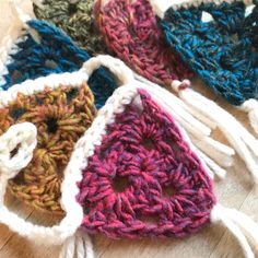 four crocheted purses sitting on top of a wooden table