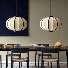 a dining room table with four chairs and two hanging lights