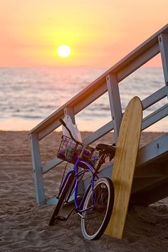 a skateboard leaning against a railing with the ocean in the background and another bike parked next to it