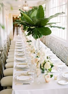 a long table is set with white flowers and place settings