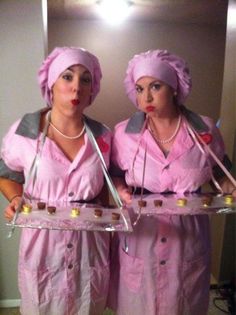 two women dressed in pink are holding trays