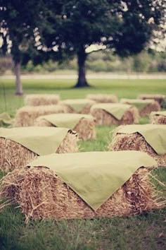 hay bales sitting in the middle of a field with trees and grass behind them