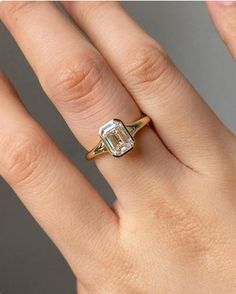 a woman's hand with an engagement ring on top of her finger, showing the center stone