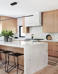 a kitchen with marble counter tops and stools next to an island in the middle