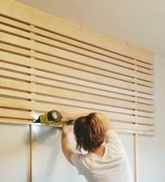 a woman is working on the wall with a drill