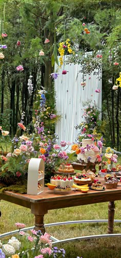 a picnic table with flowers and cake on it in the middle of a garden area