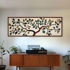 a painting on the wall above a desk with a typewriter and potted plants