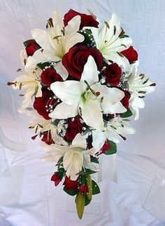 a bridal bouquet with red roses and white lilies is displayed on a white background