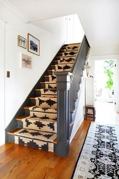 a stair case with rugs on the bottom and handrail