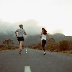 two people running down the road with mountains in the background