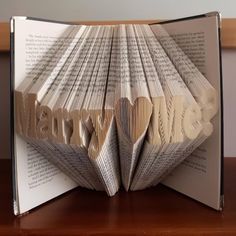 an open book with folded pages that spell out the word'love'on it