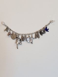 "JB Sterling bracelet with 18 charms! Each charm is marked Sterling silver and two move. The poodle has a crown and when you press it's red tongue, the eyes close and there is a bell Charm where the dinger moves. The other charms are: * surfer board * state of Hawaii * Bridesmaid * bell with moving dinger * Oregon banner * Dinosaur * Blue enamel bird * Virginia city Nevada * gold miner * octopus * state of Georgia * pineapple * totem pole * Happy birthday * Canada * Louisiana The bracelet measur Adjustable Metal Charm Bracelet With Removable Charms, Metal Bracelet Charms With Removable Details, Adjustable Silver Bracelet With Logo Charm, Metal Bracelet With Removable Charms, Silver Charm Bracelet With Logo For Gift, Silver Charm Bracelet With Logo As Gift, Silver Bracelets With Logo Charm For Gift, Silver Bracelets With Logo Charm As Gift, Adjustable Metal Name Bracelet With Charms