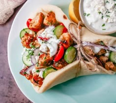 a pita sandwich with chicken, cucumbers and tzatzh next to a bowl of yogurt