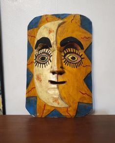 a wooden block with an image of a face painted on it's side and another piece of art in the background