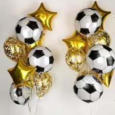 soccer balls and gold stars are arranged in the shape of balloons on a white wall