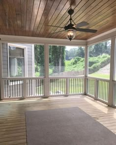 an empty porch with a ceiling fan and large rug on the floor in front of it