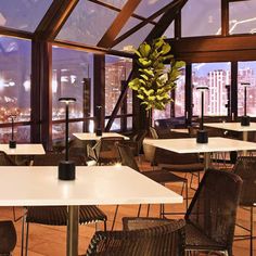 an indoor restaurant with tables and chairs overlooking the city