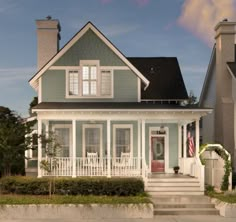 a blue house with white trim and shutters on the front door is seen in this image