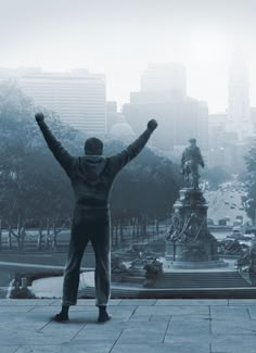 a man standing in front of a statue with his arms up