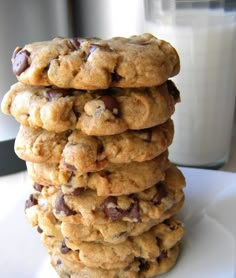 a stack of cookies sitting on top of a white plate next to a glass of milk